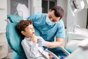Julho Laranja Campanha Dentista atendendo uma criança no consultório odontológico, com ambos sorrindo e trocando olhares amigáveis.